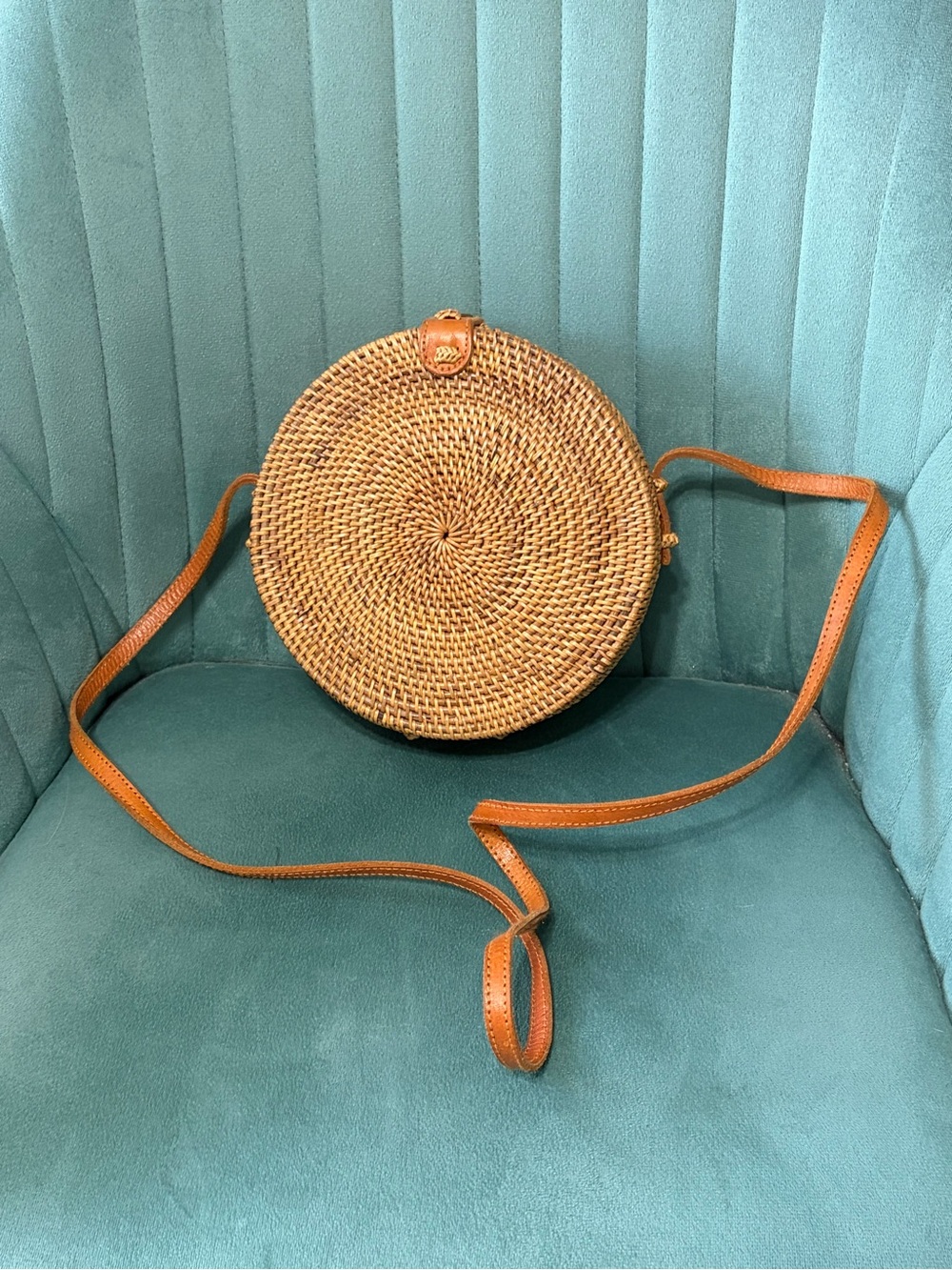 round rattan crossbody bag featuring a classic spiral pattern and a tan leather